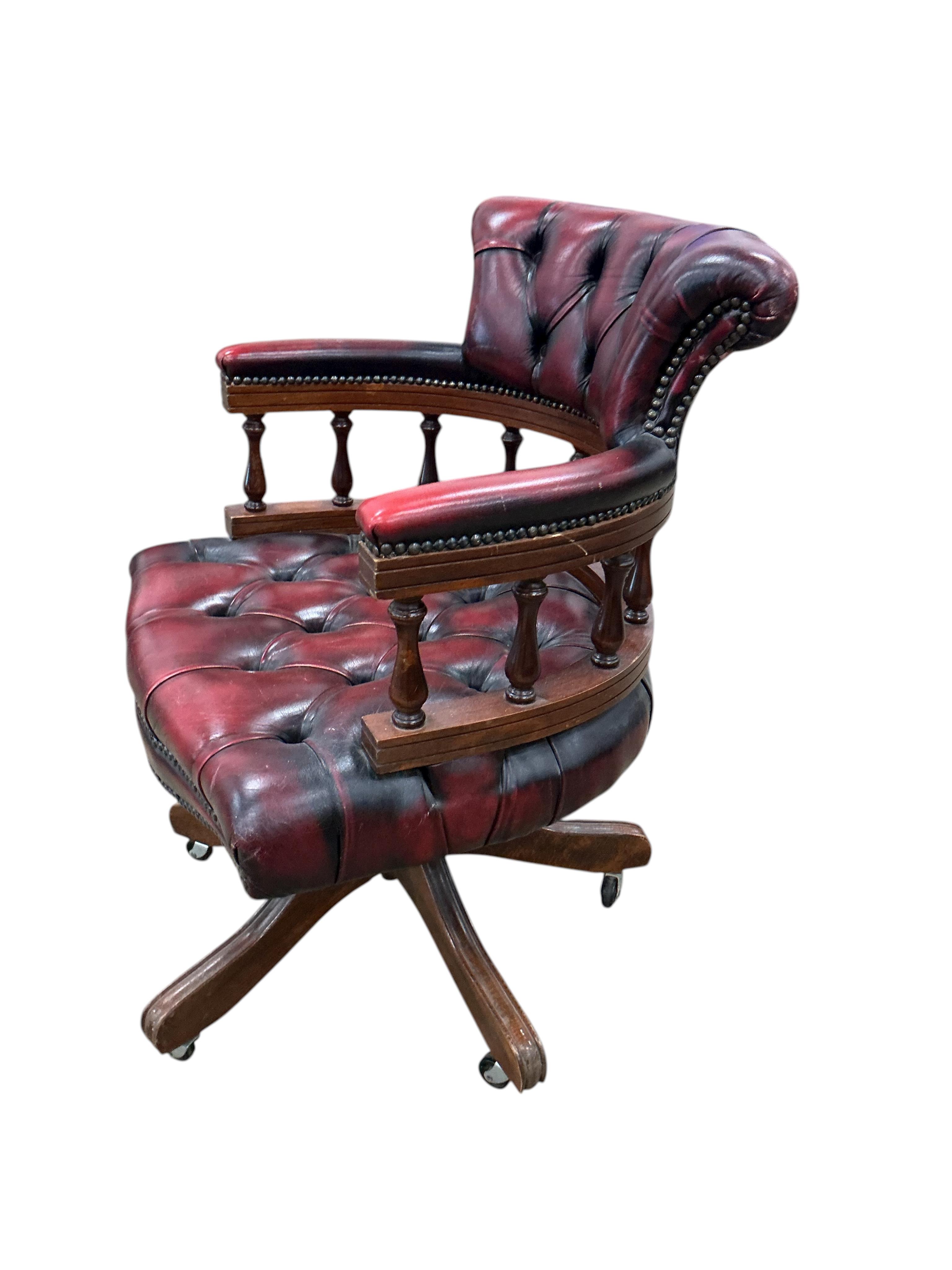 A late 20th century revolving desk chair upholstered in buttoned claret leather, width 62cm, depth 56cm, height 82cm